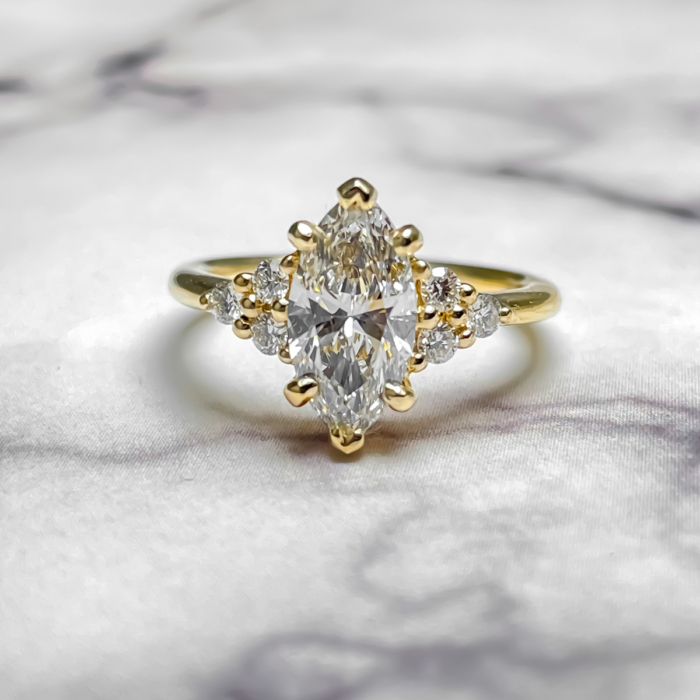 Marquise diamond engagement ring with round diamond side clusters 